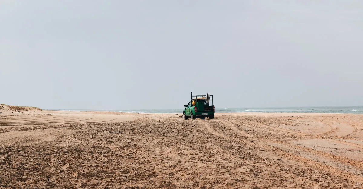 A 4x4 truck driving on the sand at the beach